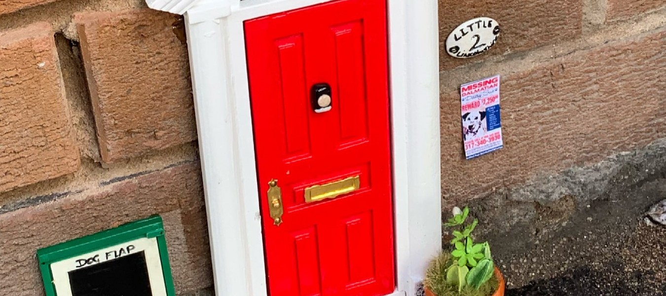 A door and doorstep with a dog flap and a dalmatian coming out, outside Spotty Dogs in Grimsby